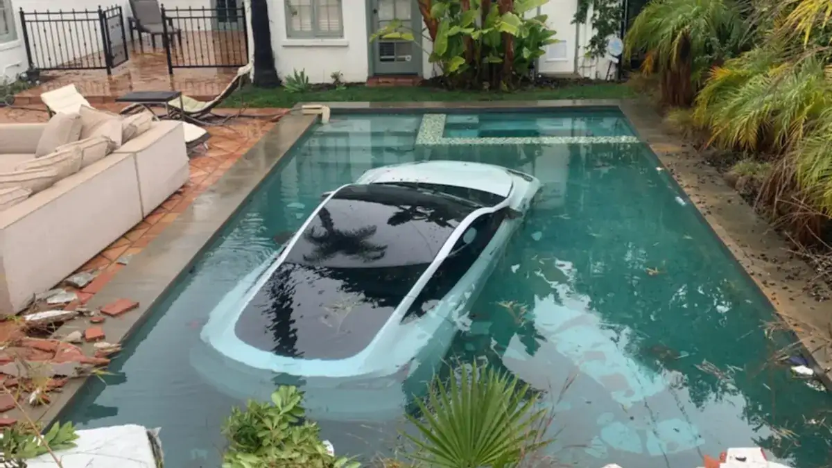 Tesla lands in a swimming pool after the driver accidentally crashes through a wall